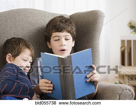 Stock Photo - Hispanic boy reading to brother. Fotosearch