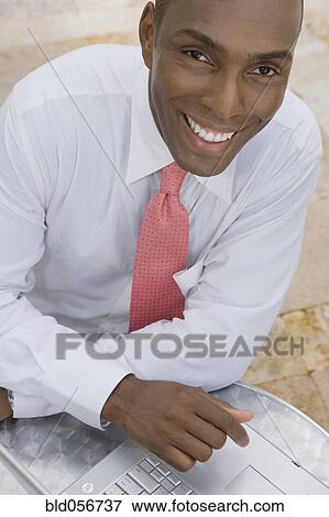 Stock Photo - Hispanic businessman next to laptop. Fotosearch