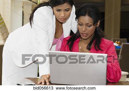 Hispanic businesswomen looking at laptop View Large Photo Image Stock Image - Hispanic businesswomen looking at laptop. Fotosearch