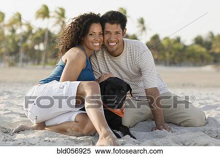 Stock Photography - Hispanic couple and dog on beach. Fotosearch