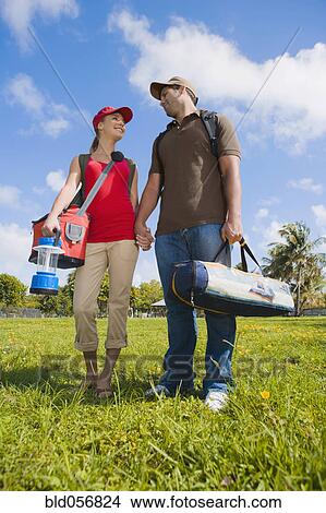 Picture - Hispanic couple carrying camping supplies. Fotosearch