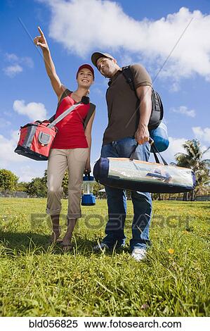 Stock Photography - Hispanic couple carrying camping supplies. Fotosearch