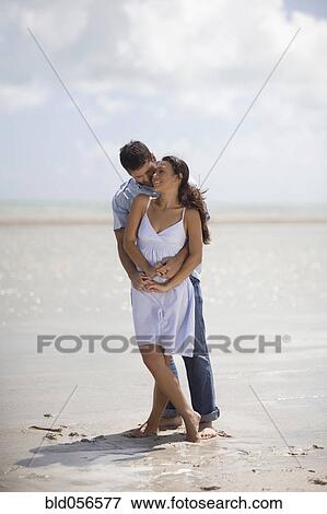 Stock Photo - Hispanic couple hugging at beach. Fotosearch