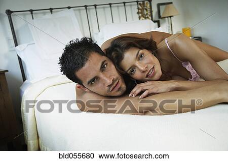 Stock Image - Hispanic couple hugging in bed. Fotosearch