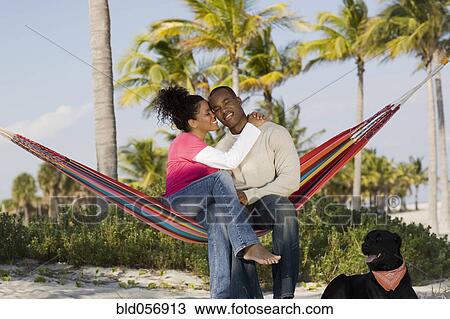 Stock Image - Hispanic couple hugging in hammock. Fotosearch