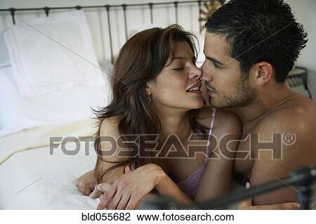 Stock Image - Hispanic couple kissing on bed. Fotosearch