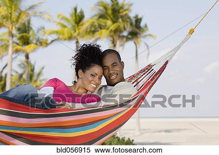 Stock Photography - Hispanic couple laying in hammock. Fotosearch