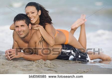 Stock Photography - Hispanic couple laying on beach. Fotosearch