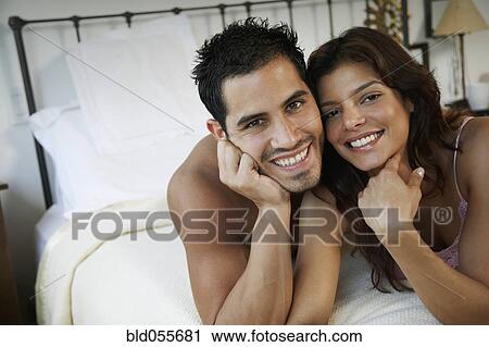 Stock Image - Hispanic couple laying on bed. Fotosearch