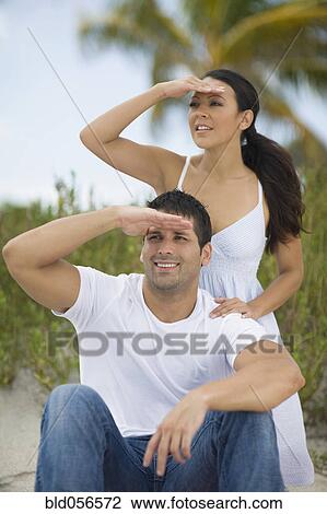 Hispanic couple shielding eyes from sun View Large Photo Image Stock Image - Hispanic couple shielding eyes from sun. Fotosearch