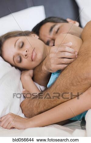 Picture - Hispanic couple sleeping in bed. Fotosearch