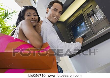Stock Image - Hispanic couple using atm. Fotosearch