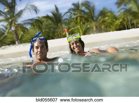 Stock Photo - Hispanic couple with snorkeling gear in water. Fotosearch