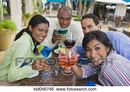 Stock Photograph - Hispanic couples toasting with cocktails. Fotosearch