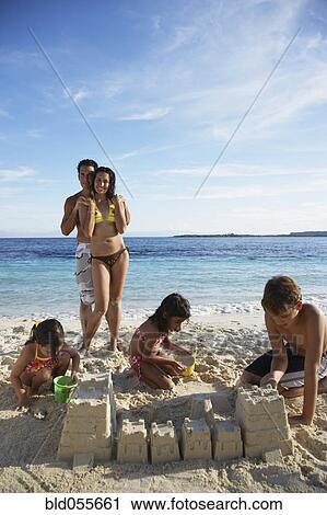 Stock Image - Hispanic family building sand castle. Fotosearch