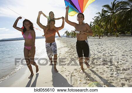 Stock Image - Hispanic family flying kite at beach. Fotosearch