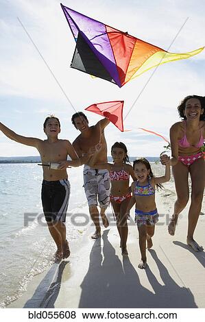 Stock Photo - Hispanic family flying kite at beach. Fotosearch