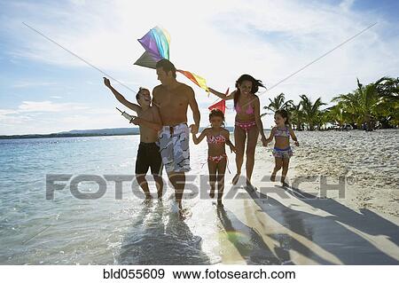 Stock Photo - Hispanic family flying kite at beach. Fotosearch