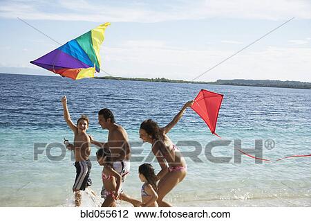 Stock Image - Hispanic family flying kites at beach. Fotosearch
