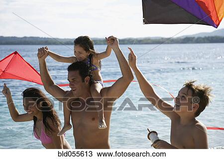 Stock Image - Hispanic family flying kites at beach. Fotosearch