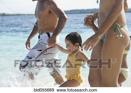 Stock Photo - Hispanic family holding hands at beach. Fotosearch