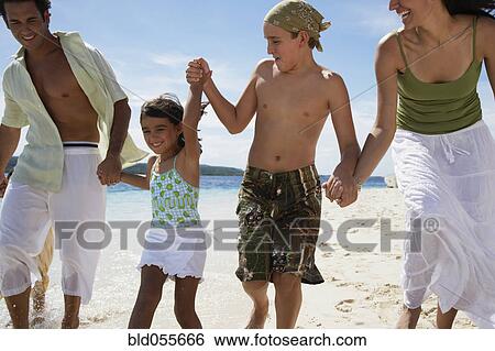 Stock Photograph - Hispanic family holding hands at beach. Fotosearch