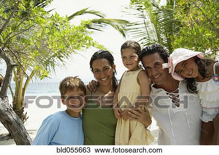 Stock Image - Hispanic family hugging at beach. Fotosearch