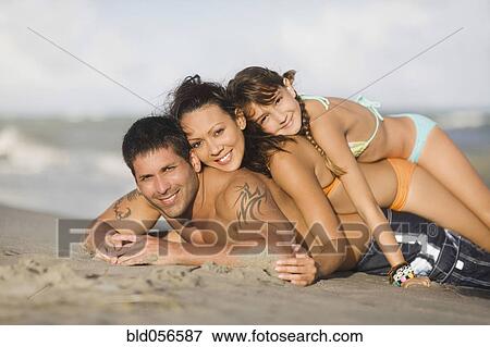 Stock Photo - Hispanic family laying on beach. Fotosearch