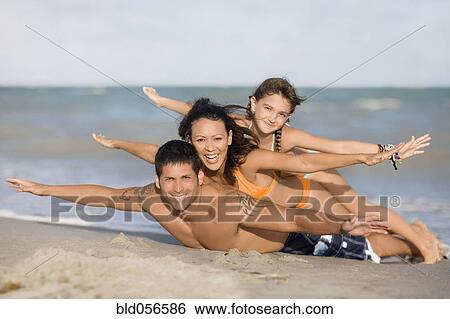 Stock Photograph - Hispanic family laying on beach. Fotosearch