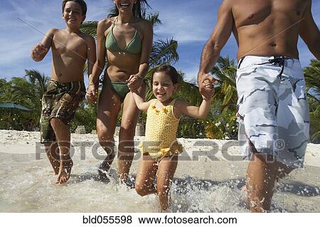 Stock Photo - Hispanic family running into water. Fotosearch
