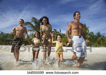 Stock Photo - Hispanic family running into water. Fotosearch