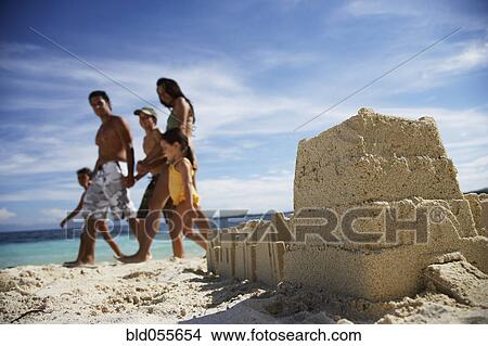 Hispanic family walking past sandcastle View Large Photo Image Picture - Hispanic family walking past sandcastle. Fotosearch