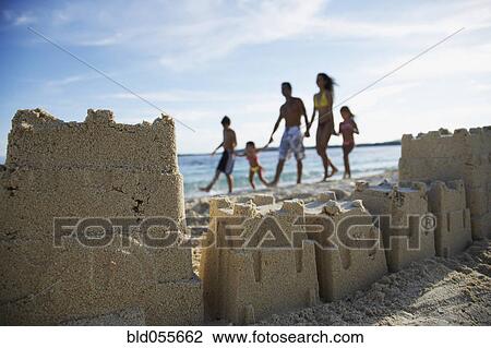 Stock Image - Hispanic family with sand castle in foreground. Fotosearch