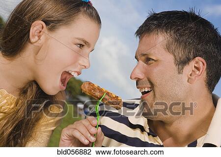 Stock Image - Hispanic father and daughter eating from same fork. Fotosearch