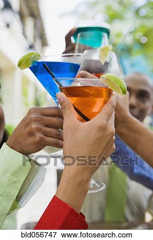 Stock Photo - Hispanic friends toasting with cocktails. Fotosearch