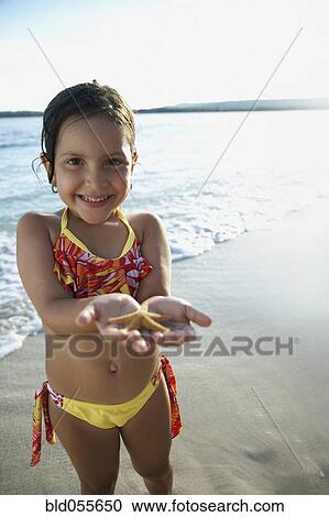Stock Image - Hispanic girl holding starfish. Fotosearch