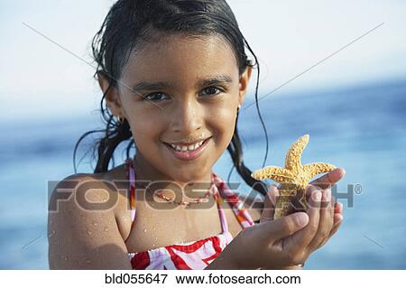 Hispanic girl holding starfish View Large Photo Image Stock Photo - Hispanic girl holding starfish. Fotosearch