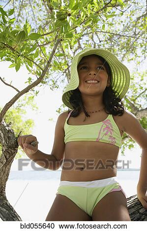 Stock Image - Hispanic girl in bathing suit under tree. Fotosearch