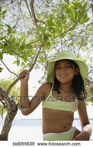Stock Photo - Hispanic girl in bathing suit under tree. Fotosearch