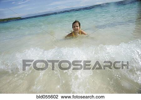 Stock Image - Hispanic girl laying in water. Fotosearch