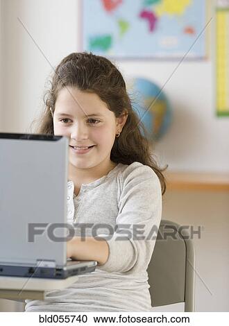 Stock Image - Hispanic girl looking at laptop. Fotosearch