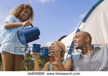 Stock Image - Hispanic girl pouring coffee for parents. Fotosearch