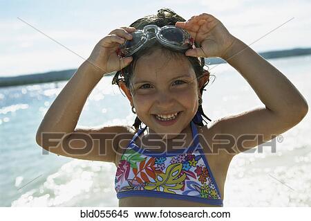 Stock Photography - Hispanic girl wearing goggles at beach. Fotosearch