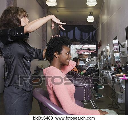 Stock Photo - Hispanic hair stylist cutting African woman’s hair. Fotosearch