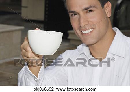 Hispanic man holding up coffee cup View Large Photo Image Stock Image - Hispanic man holding up coffee cup. Fotosearch