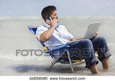 Hispanic man in beach chair with laptop View Large Photo Image Stock Image - Hispanic man in beach chair with laptop . Fotosearch