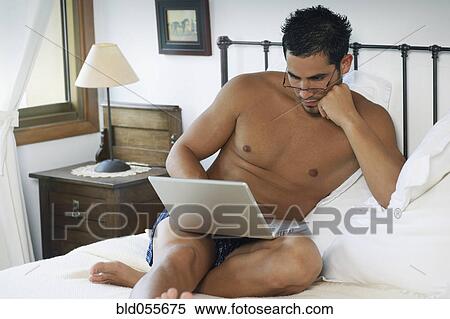Stock Photography - Hispanic man looking at laptop. Fotosearch