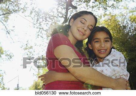 Stock Image - Hispanic mother and daughter hugging. Fotosearch