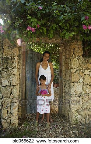 Stock Image - Hispanic mother and daughter in garden doorway. Fotosearch