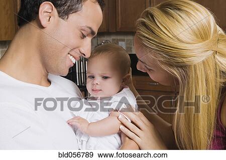 Stock Photo - Hispanic parents smiling at baby. Fotosearch